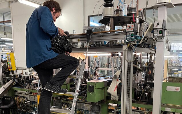 Kameramann auf Leiter filmt Maschine