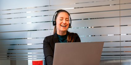 Frau mit Headset am Laptop im Büro