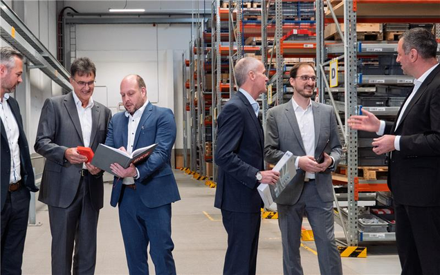 Fünf Männer im Lager bei Besprechung