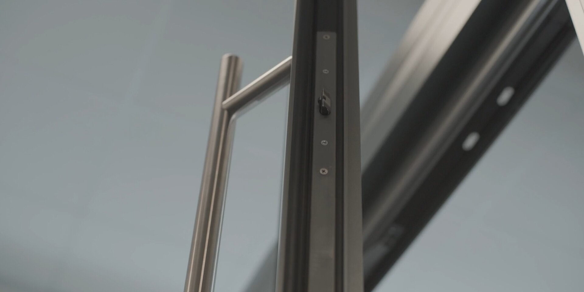 Edelstahlgriff an schwarzer Glasschiebetür und Mehrfachverriegelung