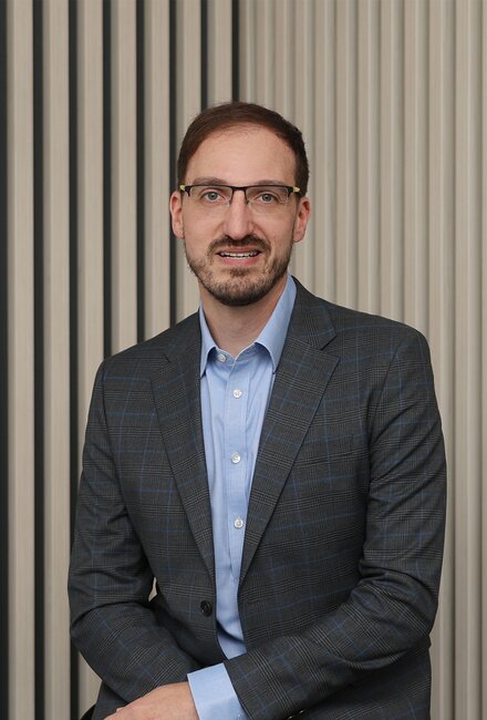 Mann mit Sakko vor gestreifter Wand